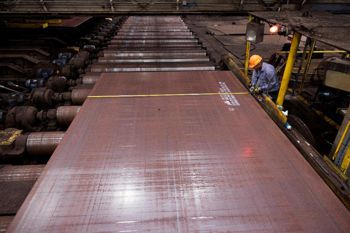 Uomo con un casco giallo che lavora su una lamiera d'acciaio